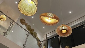 Un interior moderno con múltiples lámparas colgantes esféricas y una barandilla de vidrio con detalles decorativos.