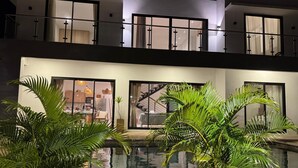 Un edificio moderno con piscina, ventanas amplias y balcón.