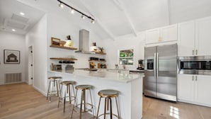 Une cuisine moderne dotée d’un îlot central, d’appareils électroménagers en acier inoxydable et de tabourets de bar.