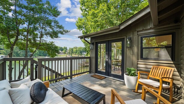 Une terrasse avec des meubles d’extérieur, une chaise en bois et une plante en pot.