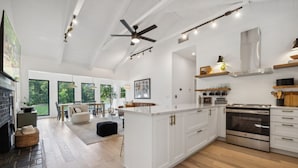 Une cuisine spacieuse avec des meubles blancs, un îlot central et un four encastré.