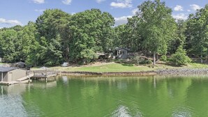 Une propriété au bord du lac, dotée d’un quai, d’un petit bâtiment et d’une maison entourée d’arbres.