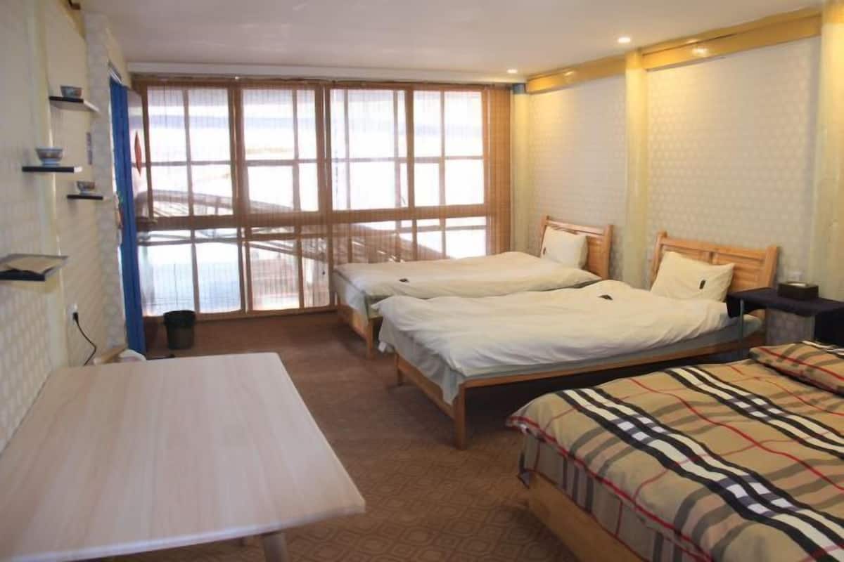Une chambre avec deux lits, une table et une fenêtre donnant sur un beau paysage.