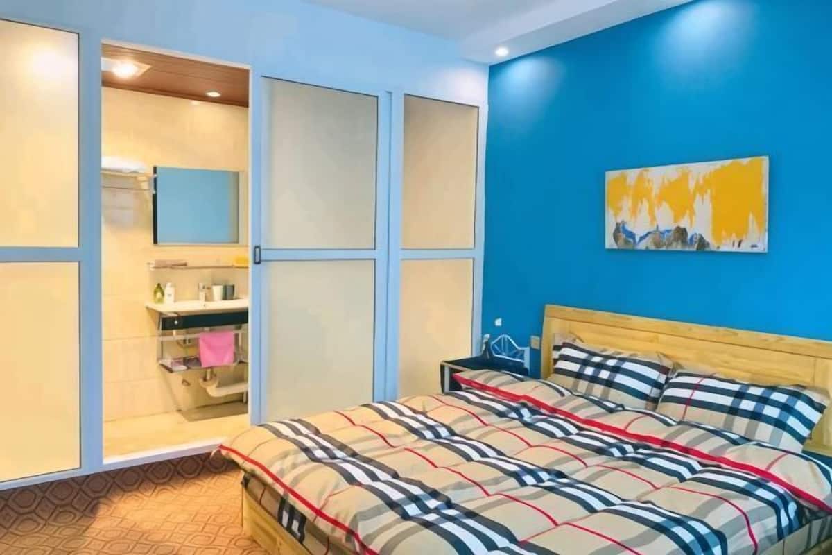 Une chambre à coucher avec un lit, une table de chevet, un miroir et un tableau accroché au mur.