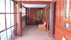 Un couloir aux murs en bois et au tapis à motifs, qui mène à une pièce contenant un lit et un banc en bois.