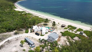 Una propiedad costera con un edificio blanco, piscina y playa.