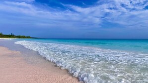 Una playa con agua turquesa transparente y una orilla arenosa.