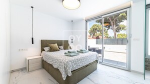 Un dormitorio con cama, mesitas de noche, un ventanal y vistas al exterior.