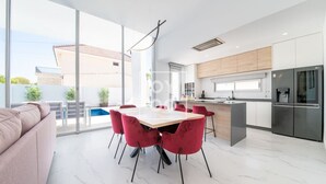 Una cocina moderna con comedor, ventanas amplias y vista a la piscina.