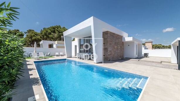 Un área moderna junto a la piscina, con una piscina azul cristalina, paredes blancas y una estructura de piedra.