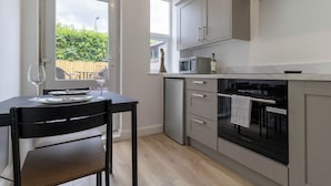 A compact kitchen with a dining area, a refrigerator, a microwave, and a stove. - Lovely Lawns Lane (Carr Gate)