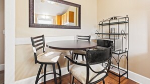 Ein Essbereich mit einem runden Tisch, vier Stühlen, einem Spiegel und einem Metallregal mit Küchenutensilien.