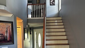 A staircase with wooden steps and a white handrail, leading to a second floor. - Charming 2-bedroom townhome with game room, WiFi, AC, only 10 min to Dollywood. (Sevierville)