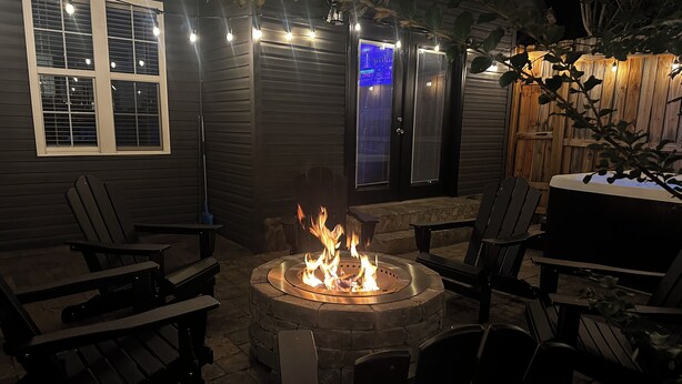 A patio with a stone fire pit, outdoor seating, and string lights. - Charming 2-bedroom townhome with game room, WiFi, AC, only 10 min to Dollywood. (Sevierville)