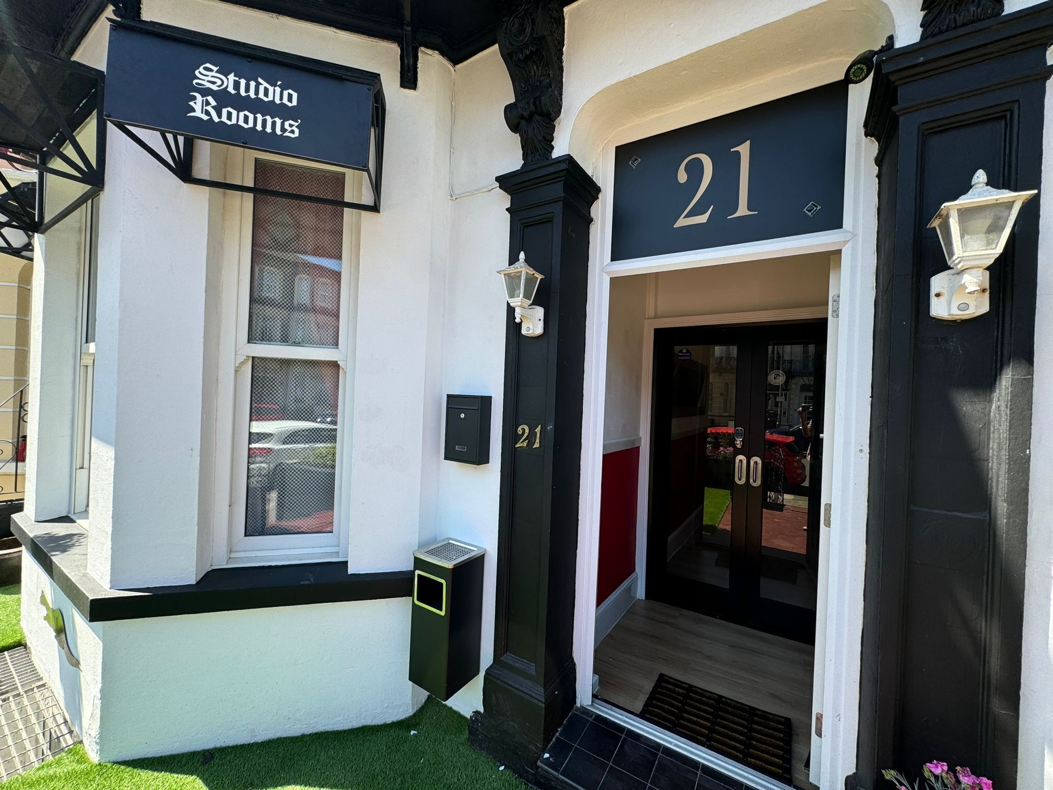 A building with a sign reading "Studio Rooms" and a door labeled "21".