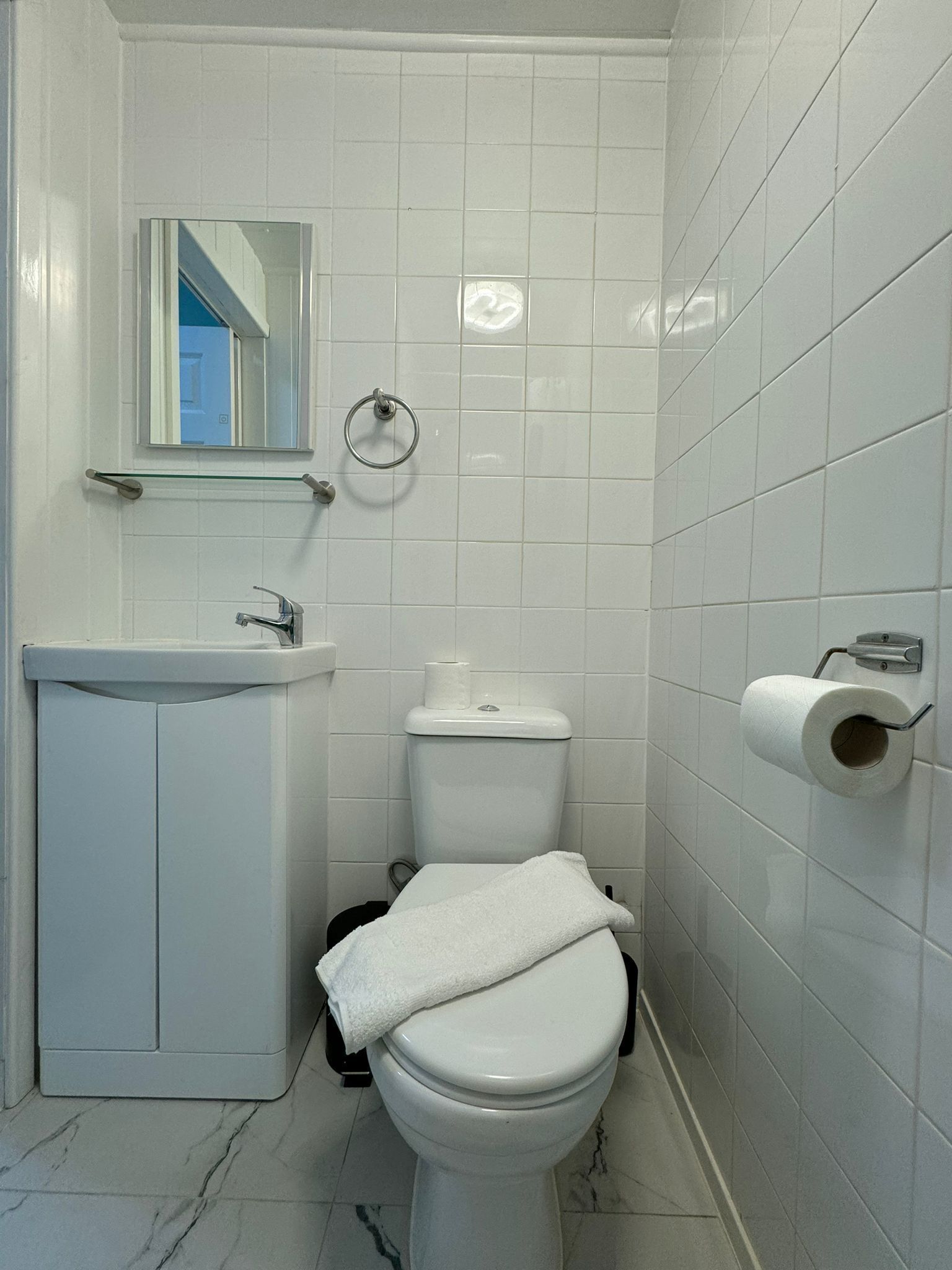 A bathroom with a toilet, sink, and mirror.