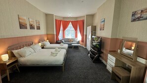 Una habitación de hotel con dos camas, un sofá, un escritorio y un televisor.