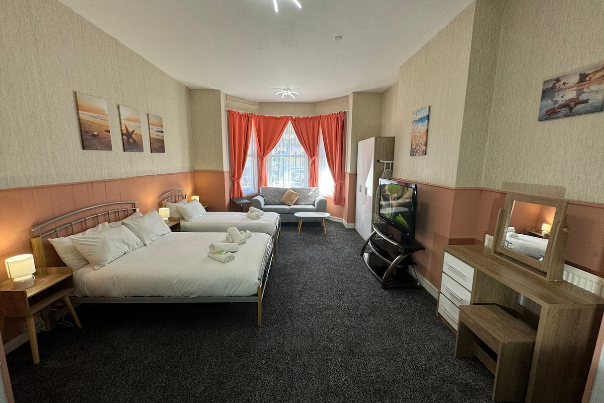 Une chambre d’hôtel avec deux lits, un canapé, un bureau et une télévision.