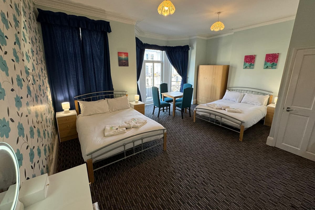 Une chambre d’hôtel avec deux lits, un bureau, une chaise et une armoire.