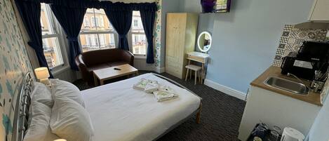 Hotelkamer met een bed, bureau, stoel, kledingkast, spiegel, televisie en kitchenette.