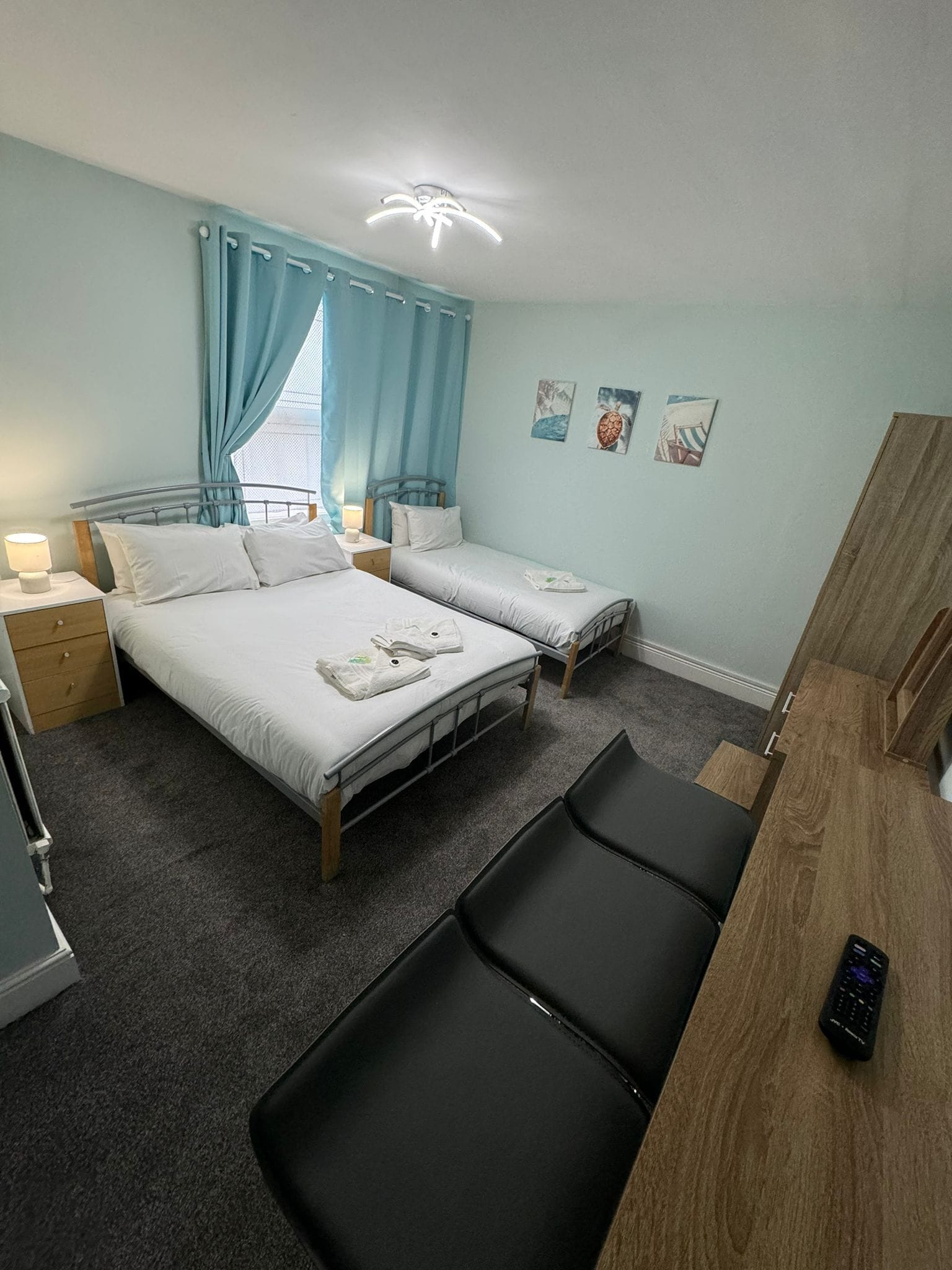 A bedroom with two beds, a desk, and a chair.