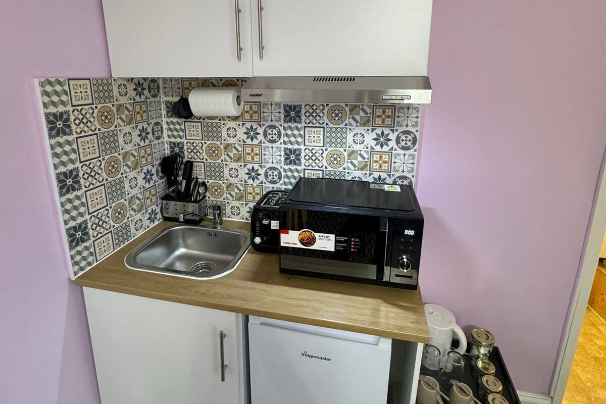 Une petite cuisine équipée d’un four à micro-ondes, d’un grille-pain et d’un petit réfrigérateur.