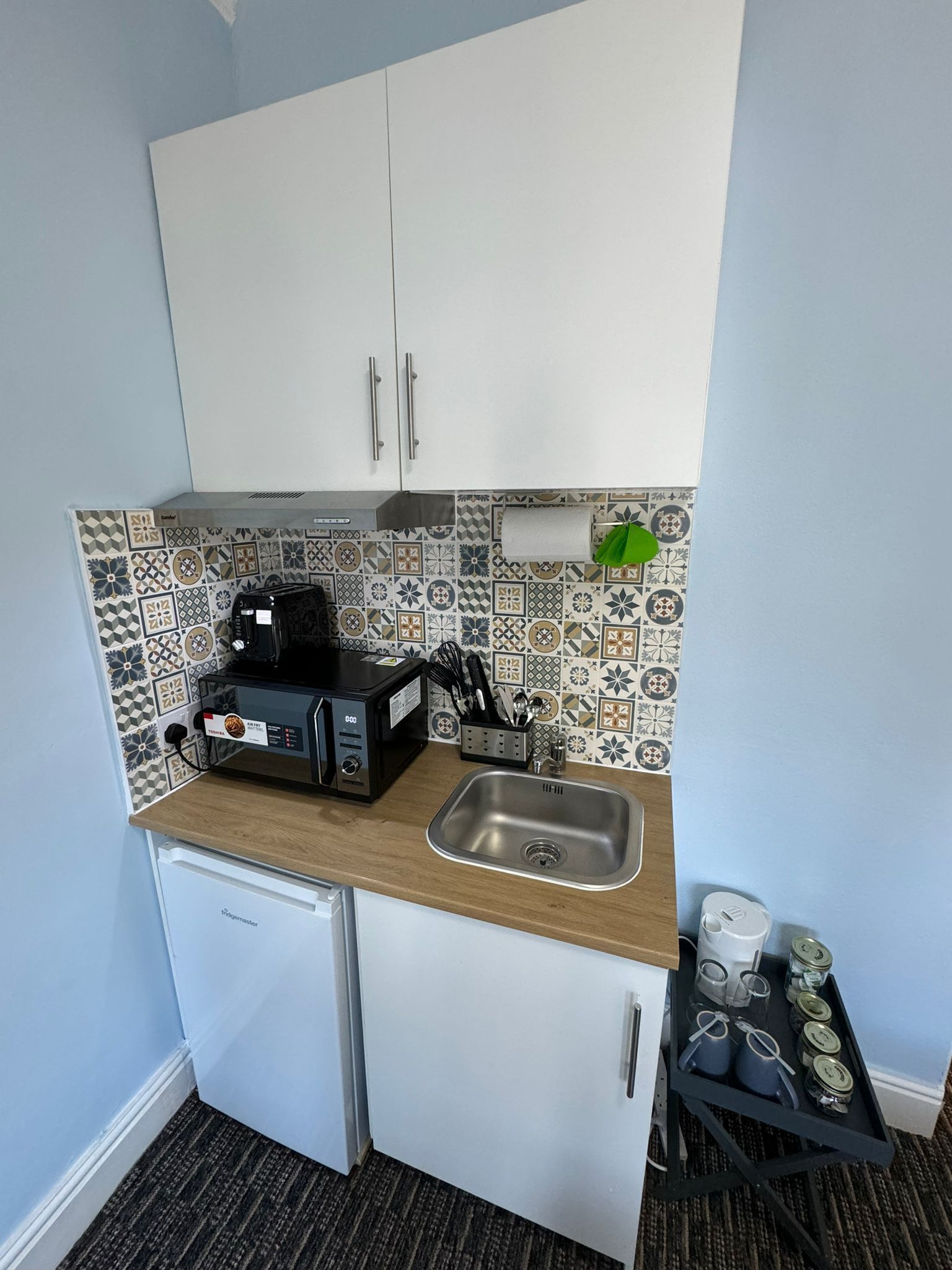 A compact kitchen with a microwave, toaster, and sink.