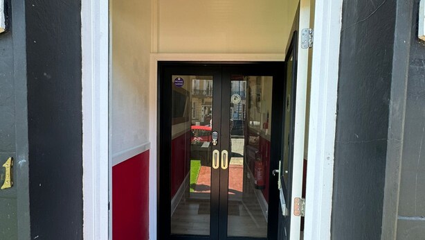 Entrada de un edificio con una puerta negra y el número 21 en la parte superior.
