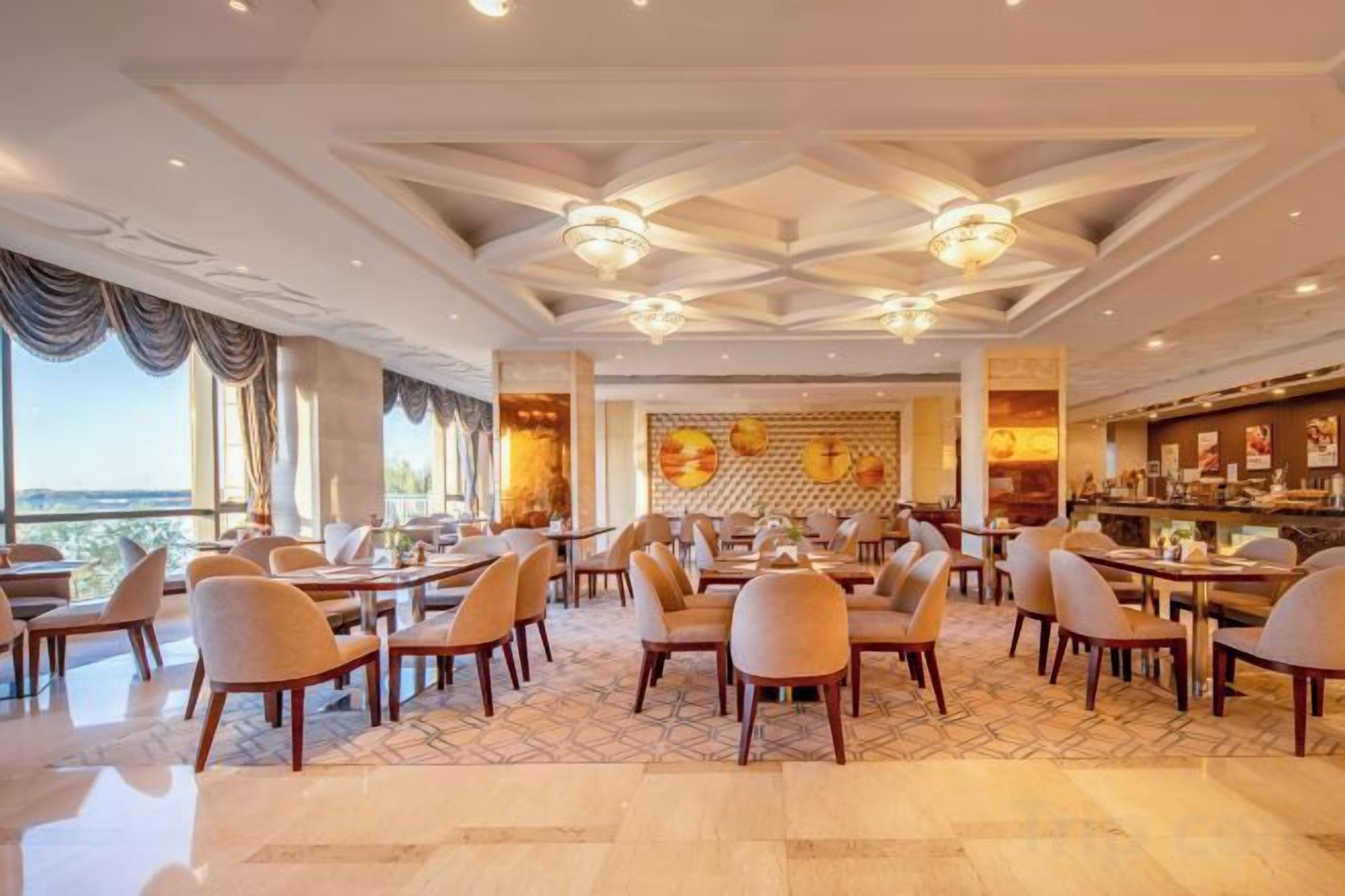 A spacious dining area with multiple tables and chairs, a bar area, and large windows offering a view.