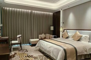 A modern hotel room with a large bed, a desk, and a chair. - Yancheng Gangbo Peninsula Hotel (Yancheng)