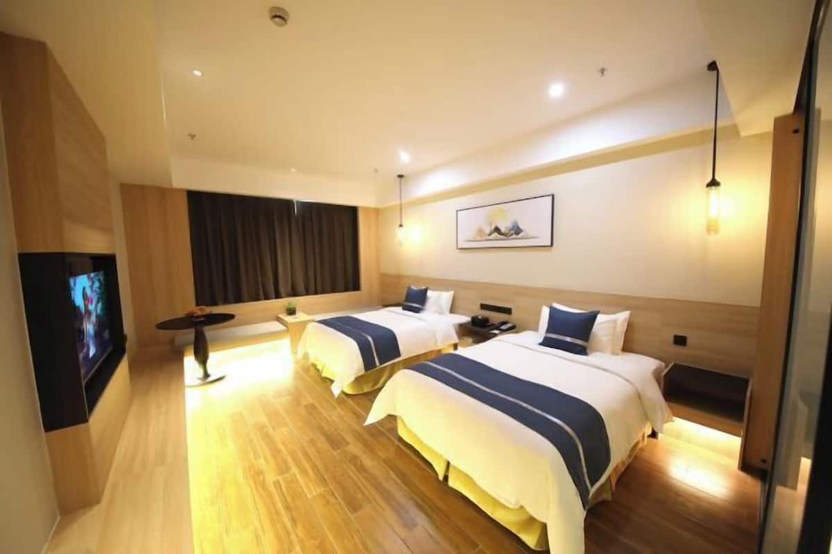 Habitación de hotel con dos camas, un televisor de pantalla plana, un escritorio y un ventanal grande.