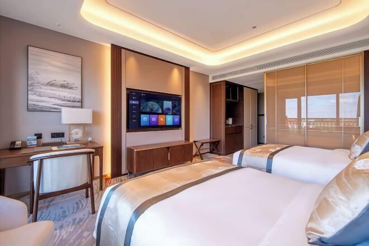 Una habitación de hotel con dos camas, un escritorio, un televisor y vistas a la ciudad.