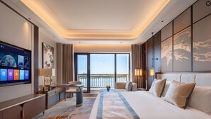 Habitación de hotel moderna con una cama grande, televisor de pantalla plana, escritorio y vista al mar.