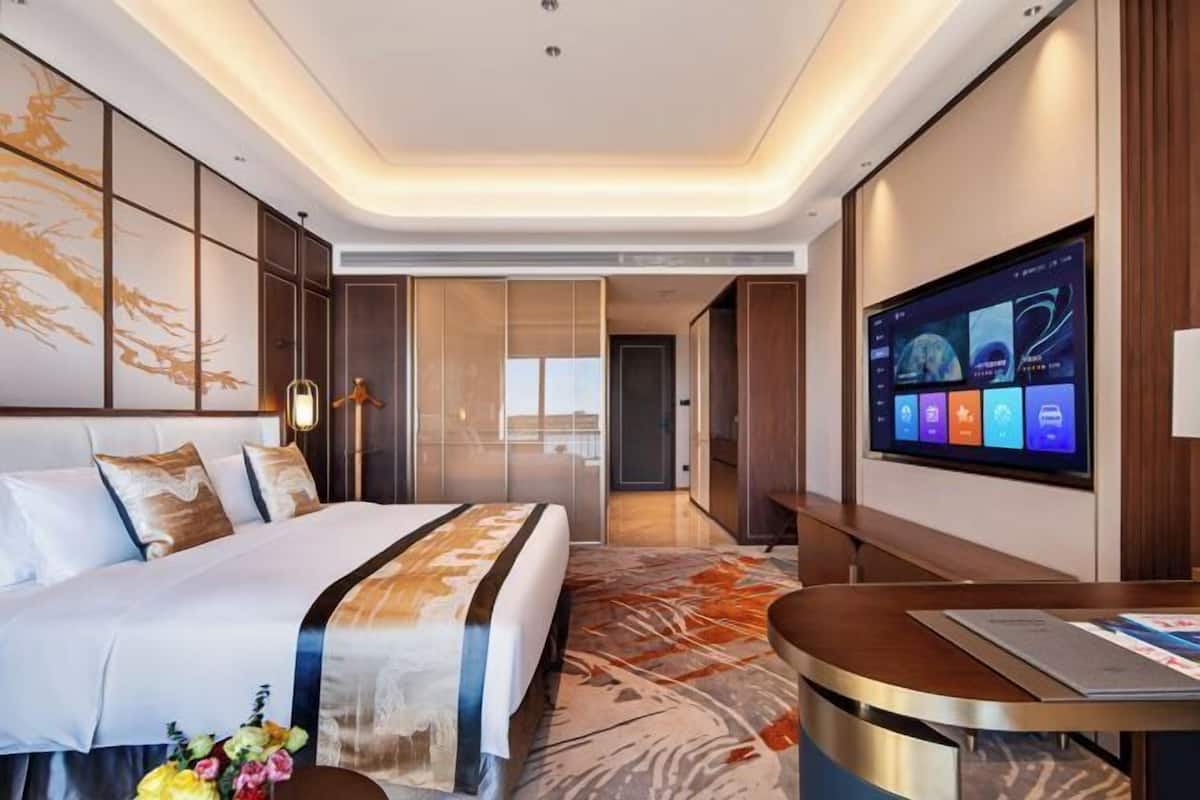 Una habitación de hotel moderna con una cama, un televisor y un escritorio.