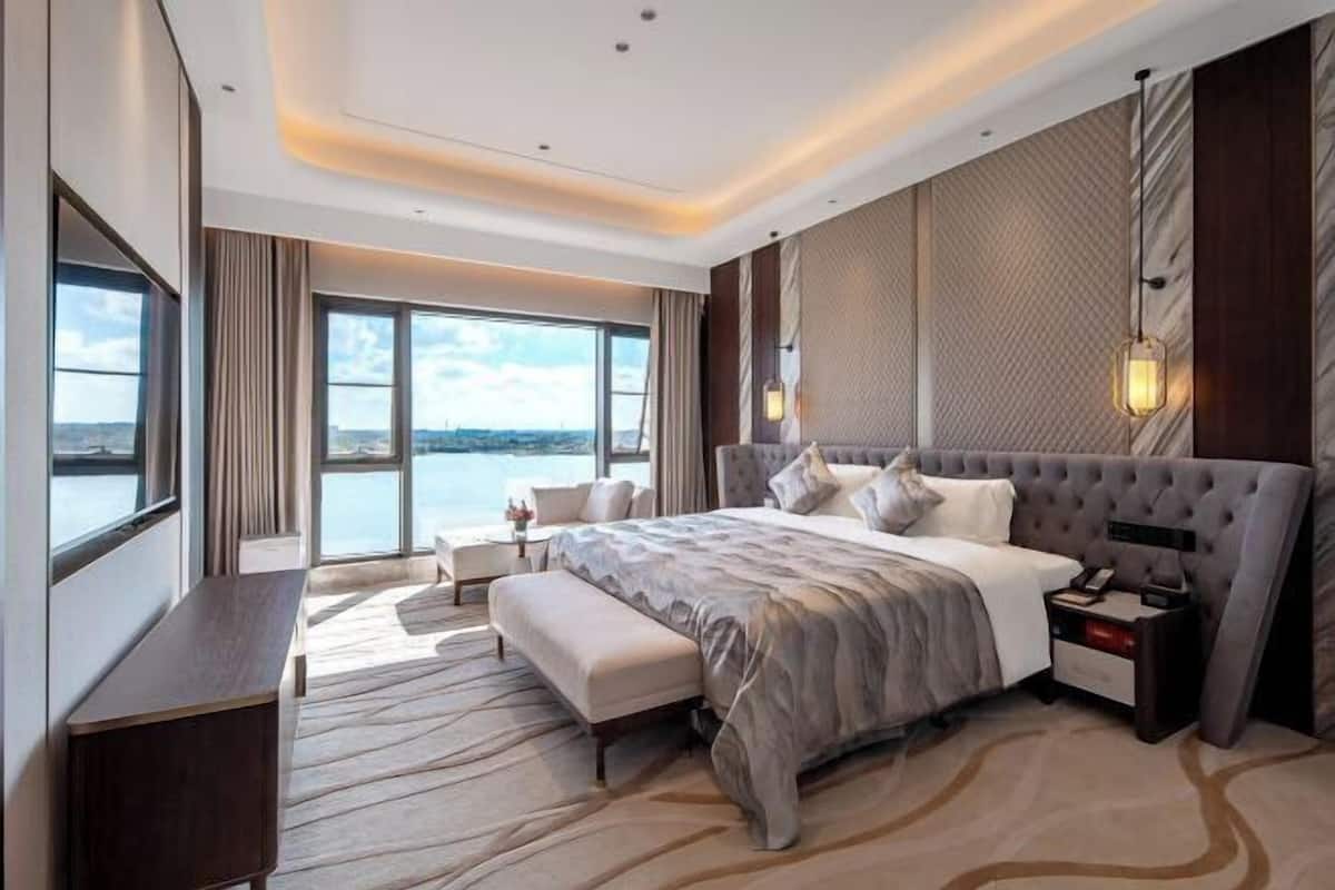 Una habitación de hotel moderna con una cama grande, un escritorio y vistas al agua.