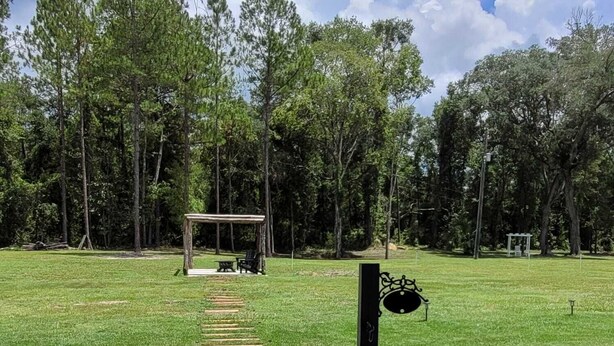 A wooden deck leading to a gazebo in a grassy park area with trees in the background. - Pequeño Refugio Cerca de Rios (Fort White)