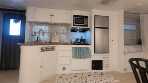 A compact kitchenette with a microwave, stove, and refrigerator. - Pequeño Refugio Cerca de Rios (Fort White)