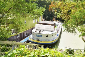 Een smalle gracht met een boot genaamd 'SANDRA' aan een groen gebouw met ramen.
