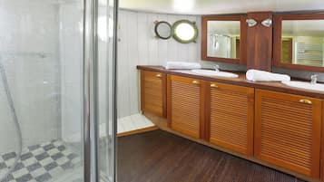 Ein Badezimmer mit Duschkabine aus Glas, Holzausstattung, einem Waschbecken und zwei Spiegeln.