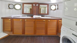 A bathroom with a wooden vanity, two sinks, and a washing machine. - Peniche Refuge Seine (Vigneux-sur-Seine)
