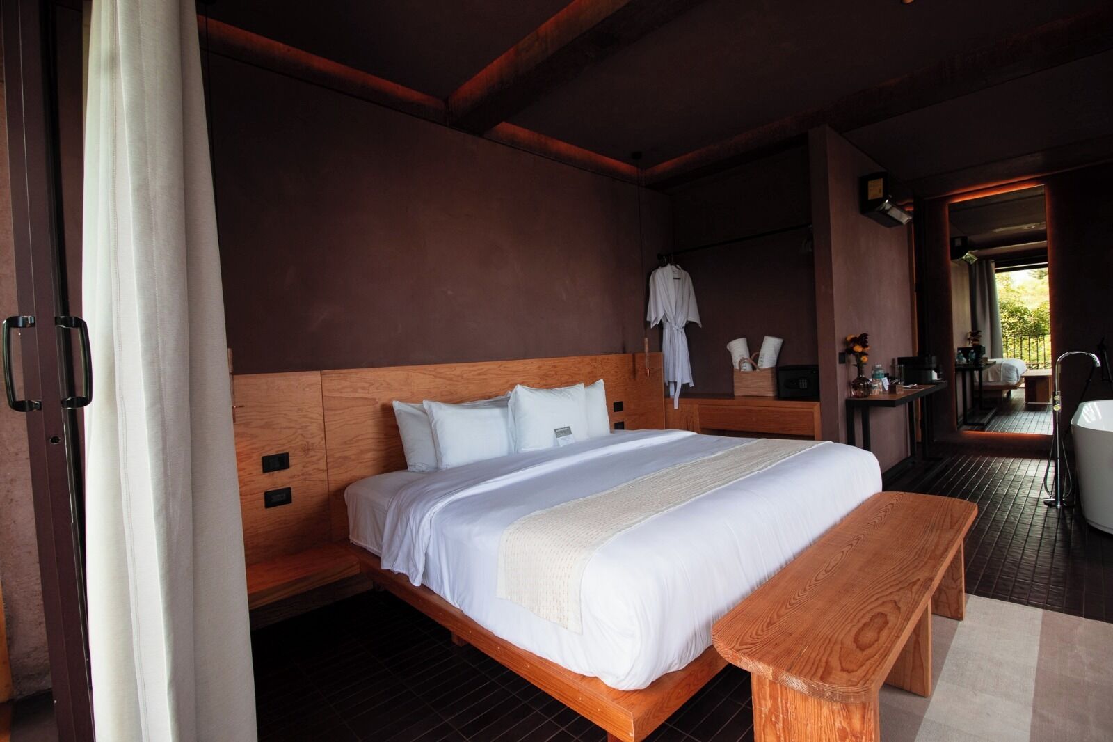 A spacious bedroom with a large bed, wooden headboard, and a bench.