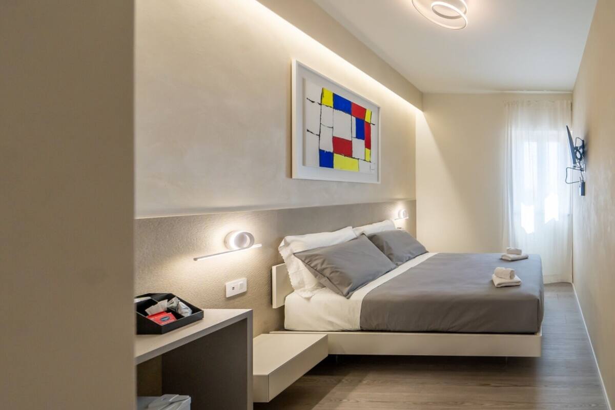 Ein modernes Hotelzimmer mit Bett, Nachttisch und einem Wandbild.