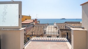 A balcony with a tiled floor and metal railing, overlooking a coastal area with a ship in the distance. - giardini inn arte (Giardini Naxos)