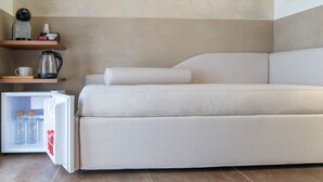 A modern, minimalist room with a sofa bed, a small refrigerator, and a coffee maker on a shelf. - giardini inn arte (Giardini Naxos)