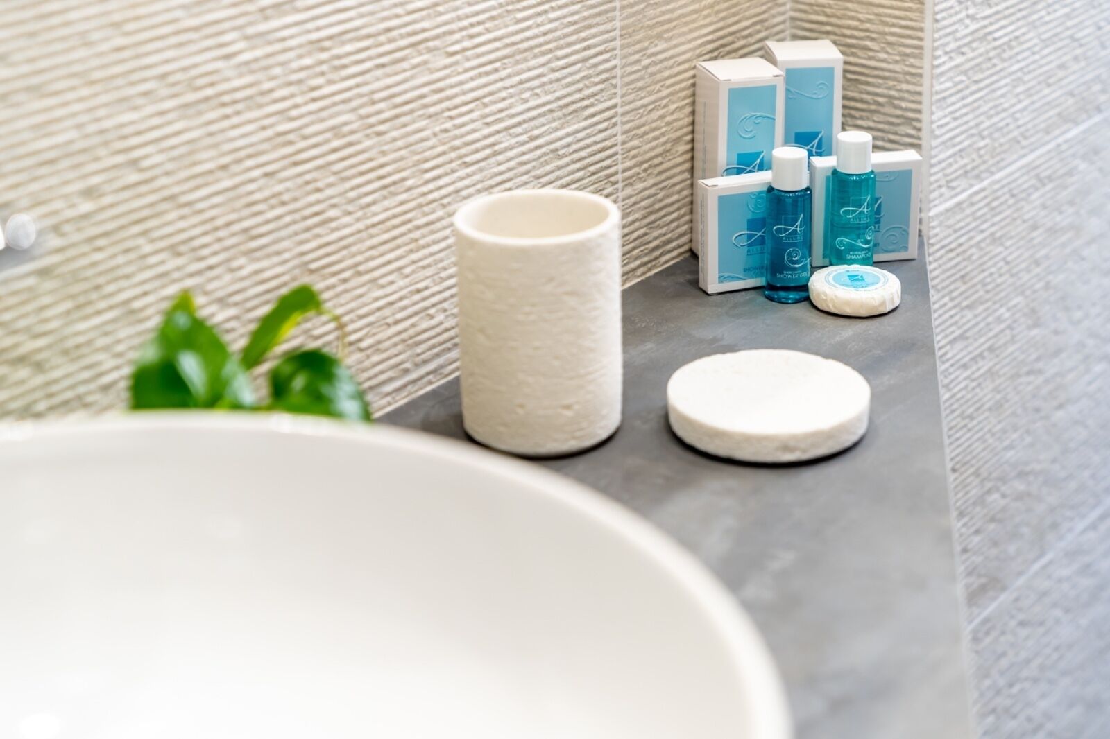 A bathroom with a white sink, a white towel, and toiletries on a gray countertop.