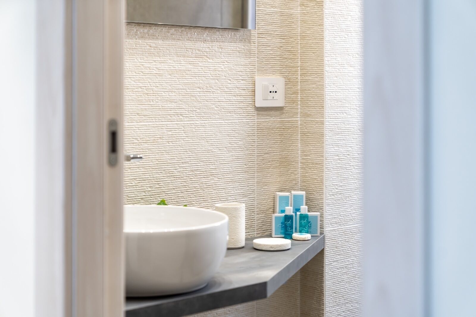 A bathroom with a white sink, a towel, and toiletries on a shelf.