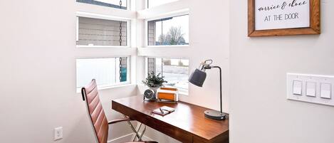 A modern office with a wooden desk, leather chair, and a motivational quote on the wall.