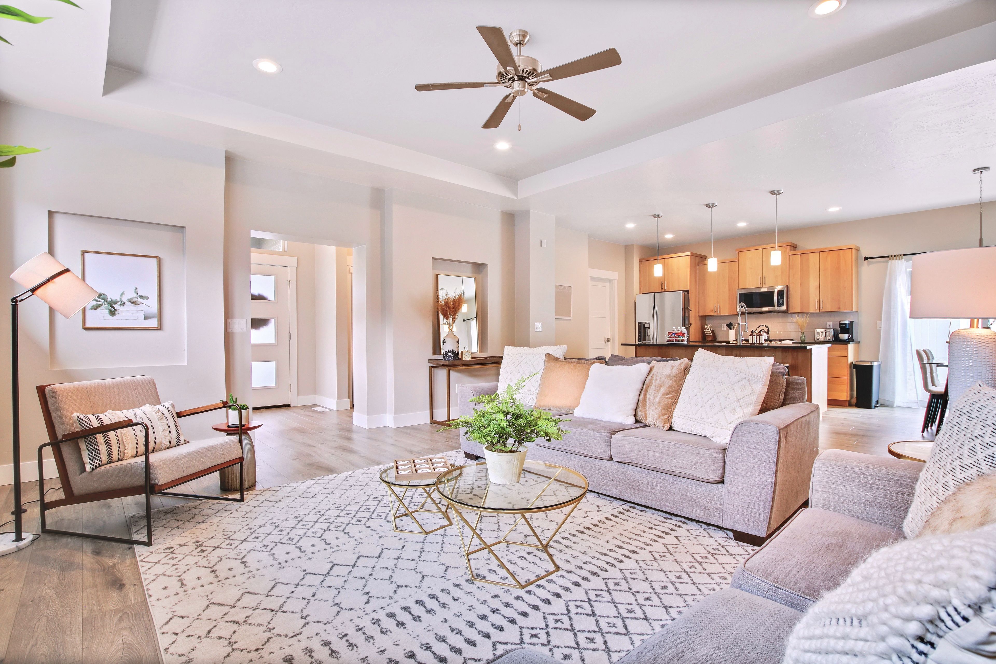 A spacious living room with a sofa, armchairs, a coffee table, and a ceiling fan.