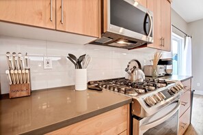 Una cocina moderna con armarios de madera, una estufa de acero inoxidable y un microondas empotrado.