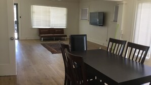 Un coin repas avec une table et des chaises en bois foncé, un canapé marron et un ventilateur de plafond.